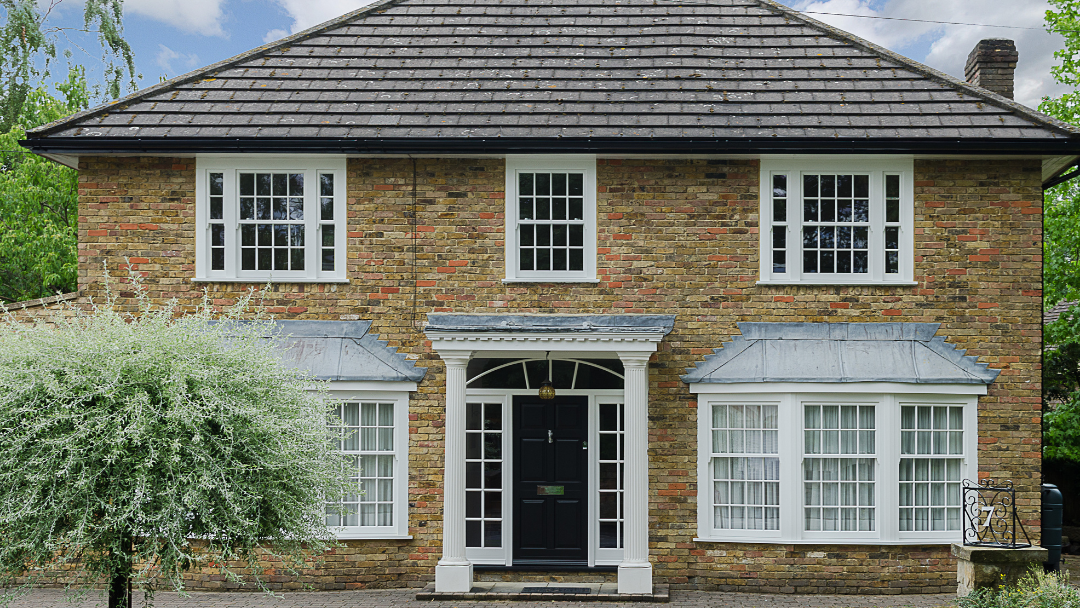Georgian style house with three timber sash windows, two timber bay windows and timber front door with side panels.