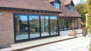 Two black aluminium bi-fold doors leading out to a patio