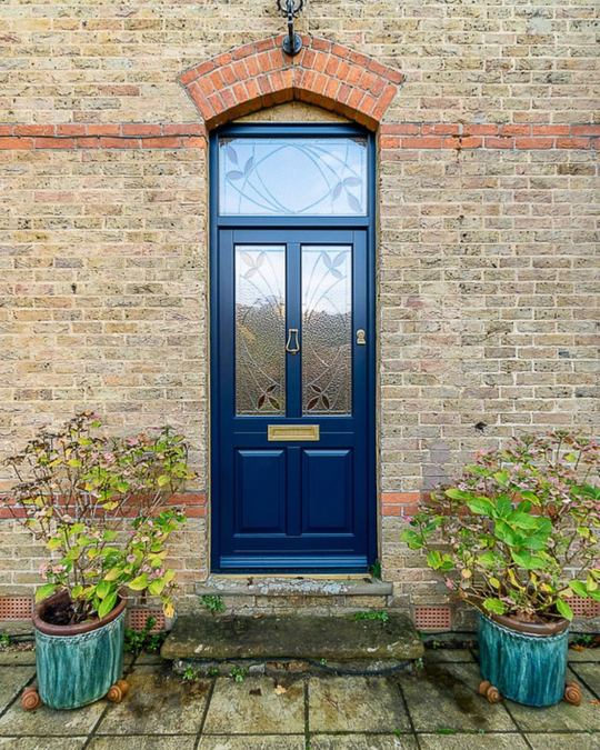 Blue timber front door in brick house with custom stained glass
