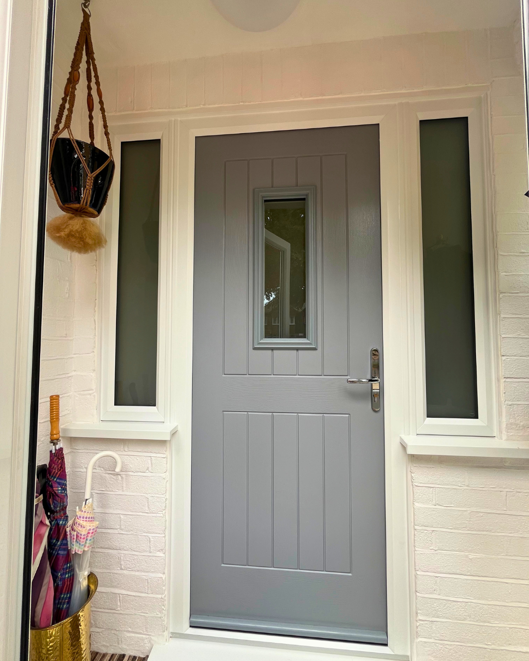 Grey composite front door in white brick house with chrome furniture