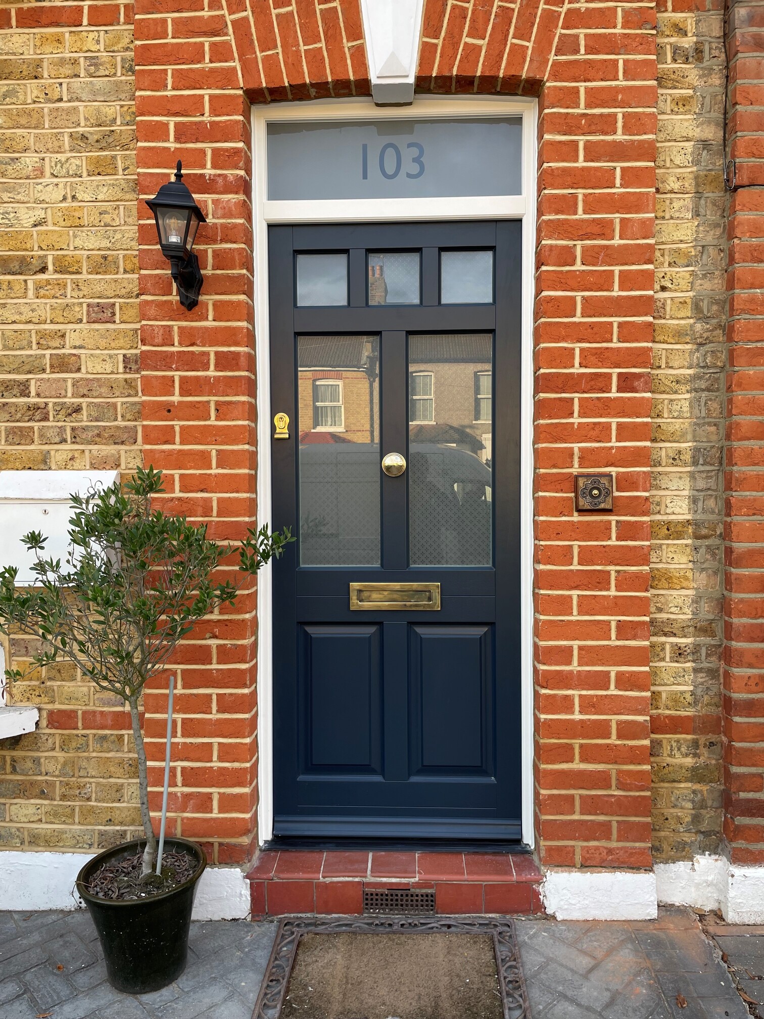 Dark navy front door in timber with brass furniture