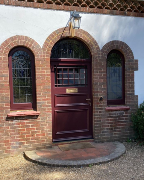 Burgundy timber doors with surround and custom stained glass