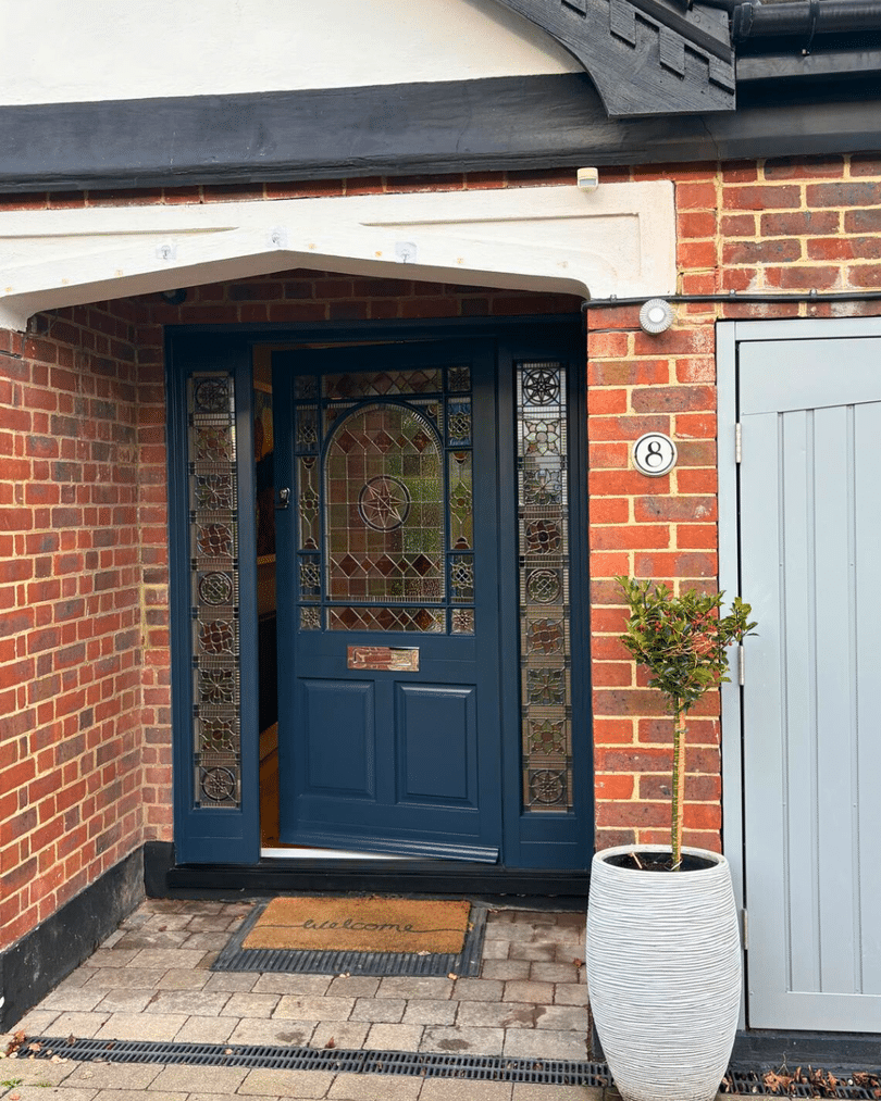 Blue timber front door with sidelights, ornate stained glass and polished chrome furniture in Harewood Grey