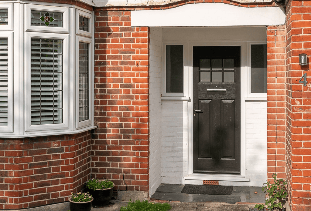 1930s red brick British semi detached house black panelled front door white windows traditional tiled porch